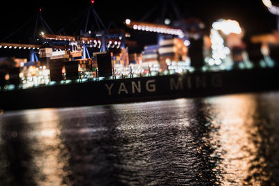 Close-up of illuminated city by river at night