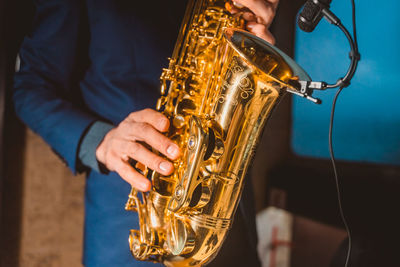 A man plays a saxophone with a microphone attached close up