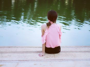 Rear view of woman with umbrella on lake