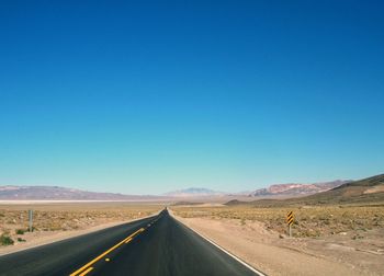 Road amidst landscape against clear blue sky