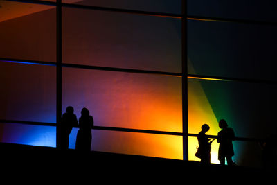 Silhouette people standing against orange sky