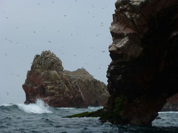 Rock formations by sea against sky