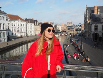 Beautiful woman standing by canal in city