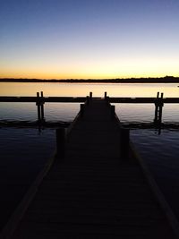 Pier in sea at sunset