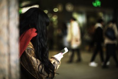 Side view of woman using mobile phone while standing outdoors