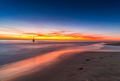 Scenic view of beach against sky at sunset