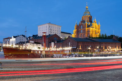 Night cityscape with illuminated uspensky cathedral and an old lighthouse boat in the foreground.