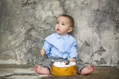 Cute boy looking away while sitting outdoors