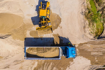 Aerial view of bulldozer pouring sand into truck