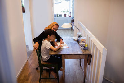 High angle view of mother and son reading book at home