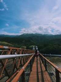 Rear view of woman walking on footbridge