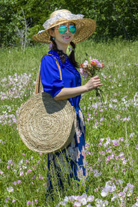 Full length of woman wearing hat standing on field