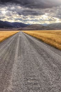 Road amidst field against sky