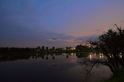 Scenic view of lake against cloudy sky during sunset