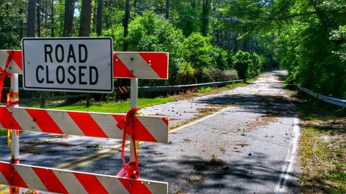 Road closed sign on barricade against trees