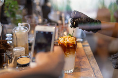Close-up of hand holding drink on table