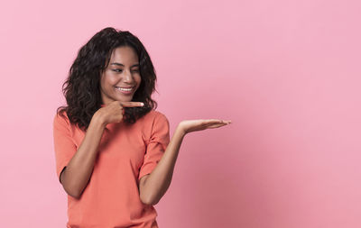 Portrait of a smiling young woman against pink background