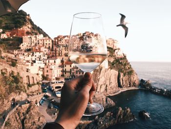 Cropped hand holding wineglass against buildings