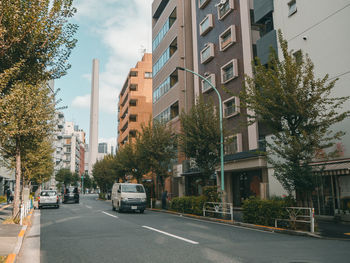 Road by buildings in city against sky