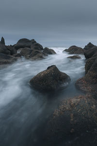 Rocks in sea against sky