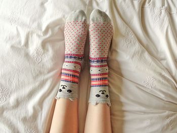 Low section of woman wearing socks on bed