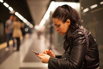 Side view of woman using smart phone at subway station