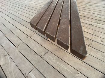High angle view of wooden bench on footpath
