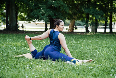 Happy confident smiling plus size curvy woman doing yoga stretching pilates workout, exercising