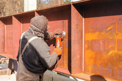 Side view of man holding camera while standing outdoors