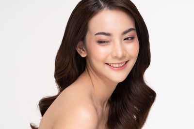 Close-up portrait of a smiling young woman over white background