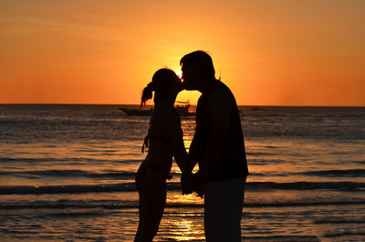 Couple kissing on beach at sunset