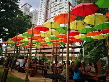 People sitting on chairs at sidewalk cafe in city