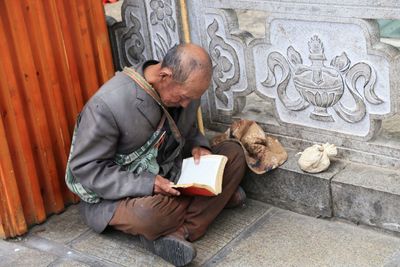 Full length of man reading book on ground