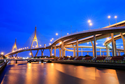 Illuminated bridge over river against sky at night