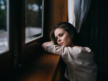 Young woman looking through window