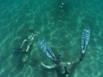 Full length of shirtless people swimming undersea