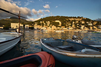 Boats moored in river by city against sky