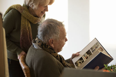 Senior couple looking at photo album surrounded by cardboard boxes in an empty room