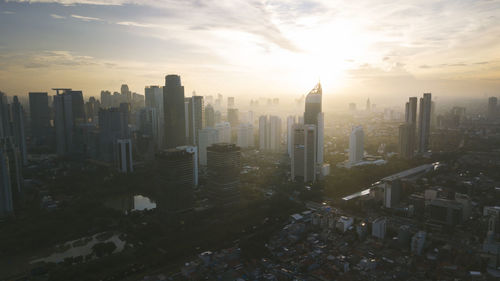 Aerial view of buildings in city against sky during sunset