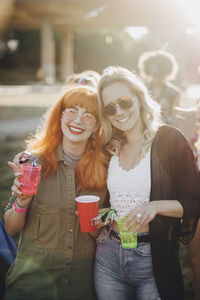 Portrait of smiling male friends enjoying drinks in concert on sunny day