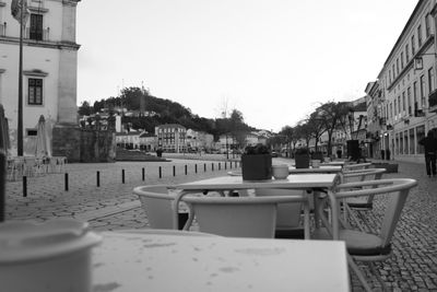 Empty sidewalk cafe in city against clear sky