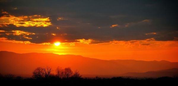 Scenic view of silhouette mountains against romantic sky at sunset