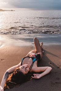 Woman lying at beach during sunset