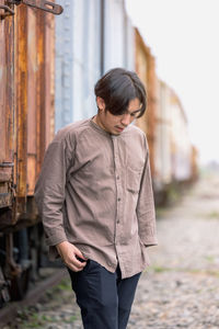 Portrait of smiling handsome asian man standing at public train station. young man standing in old