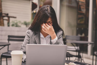 Tired businesswoman sitting at table in cafe