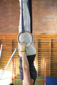 Midsection of gymnast hanging upside down using gymnastic rings at gym