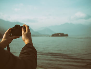 Rear view of man photographing sea against sky