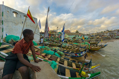 Rear view of boy on boat against sky