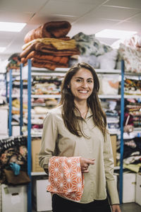 Portrait of female fashion designer with patterned fabric standing at workshop