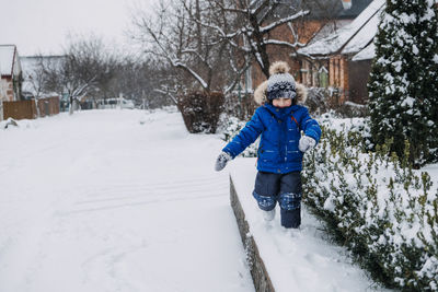 Best outdoor winter activities for kids. cute kid boy in blue winter jacket playing snowballs on